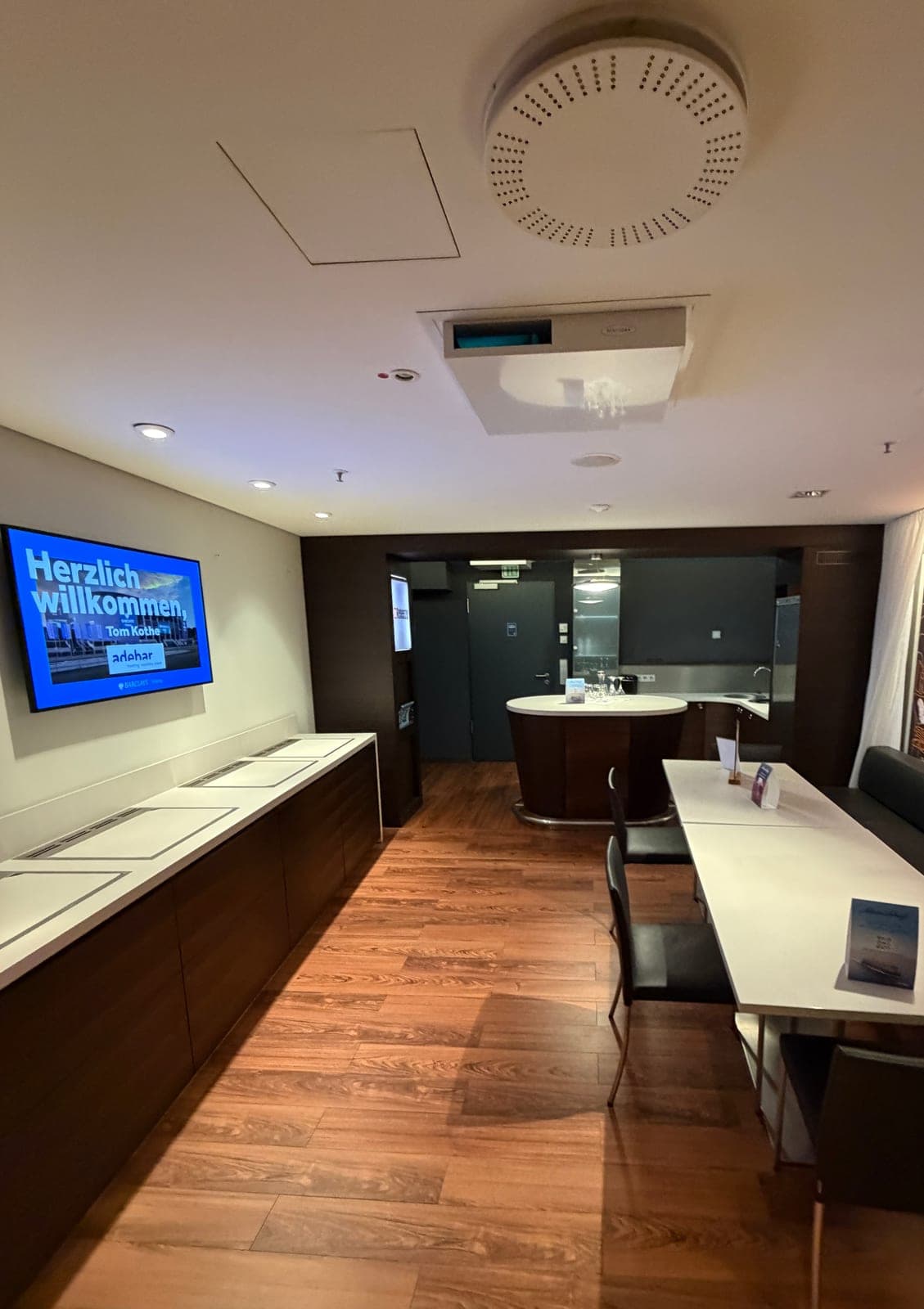 Blick in die adebar-Loge in der Barclays Arena Hamburg mit Empfangsscreen, Theke und Sitzbereich